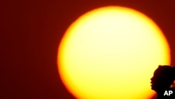 资料照片：2023年8月20日，中西部地区密苏里州堪萨斯城持续处于三位数的高温中，一位女性在夕阳下的侧影。(美联社照片)