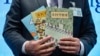 FILE - Senior superintendent of Police National Security Department poses with evidence including three children's books on stories that revolve around a village of sheep which has to deal with wolves from a different village, at a press conference in Hong Kong, July 22, 2021. 