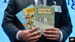 FILE - Senior superintendent of Police National Security Department poses with evidence including three children's books on stories that revolve around a village of sheep which has to deal with wolves from a different village, at a press conference in Hong Kong, July 22, 2021. 