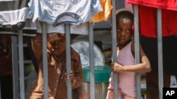 Children look through a fence at a shelter for families displaced by gang violence, in Port-au-Prince, Haiti, March 13, 2024. 