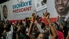 Pessoas reúnem-se em frente à sede do candidato Bassirou Diomaye Faye, em Dakar, a 24 de março de 2024, enquanto se esperam os resultados das eleições presidenciais senegalesas. 