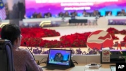 FILE - A delegate member watches Indonesian Finance Minister Sri Mulyani Indrawati deliver her speech on his tablet during the opening session of the ASEAN Finance Ministers and Central Bank Governors meeting in Jakarta, Aug. 25, 2023. 