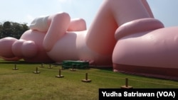 Boneka balon raksasa berbentuk kelinci berwarna merah muda karya pekerja seni asal AS, KAWS, di Candi Prambanan, Sleman, Yogyakarta, Kamis, 24 Agustus 2023. (Foto: Yudha Satriawan/VOA)