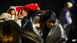 FILE - Two women from Cuba try to keep warm after crossing the border from Mexico and surrendering to authorities to apply for asylum on Nov. 3, 2022, near Yuma, Ariz.