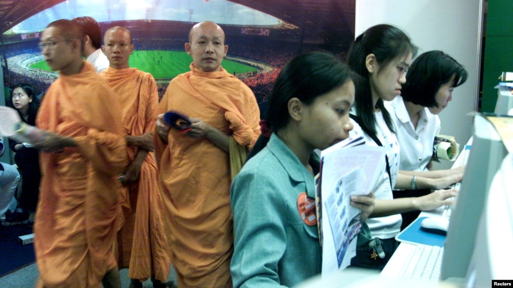 FILE - Thai Buddhist Monks walk past a line of internet users at an internet expo on May 25, 2000. (REUTERS/File photo)