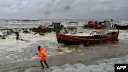 Seorang pria menarik perahu nelayan ke pantai sebagai tindakan pencegahan saat hujan turun di Kuakata, Bangladesh, pada 26 Mei 2024, menjelang datangnya topan Remal. (Foto: AFP)