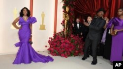 Angela Bassett, left, and Courtney B. Vance, as he takes her picture, arrive at the Oscars on Sunday, March 12, 2023, at the Dolby Theatre in Los Angeles.