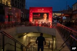 People walk down into a metro station in front of an election kiosk of MeRA25 party in Athens, on Monday, May 15, 2023.