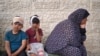 Injured Palestinian boys wait with their families to identify the bodies of relatives killed in Israeli bombardment, in the yard of the Al-Aqsa Martyrs Hospital in Deir al-Balah in the Gaza Strip on May 11, 2024.