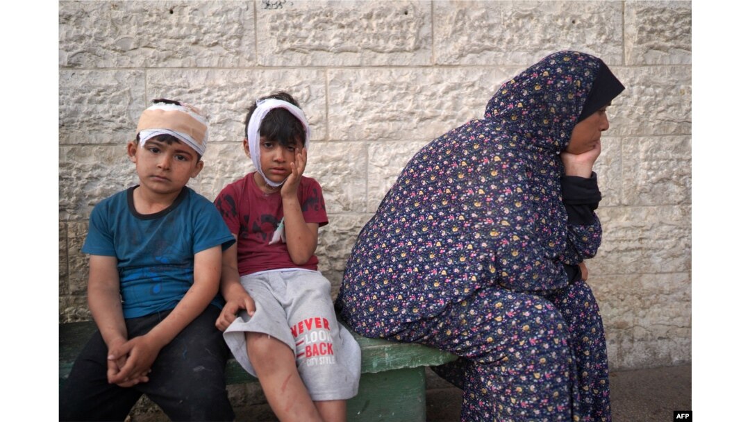 Dua anak laki-laki Palestina bersama kerabat di RS Martir Al-Aqsa di Deir al-Balah, di Jalur Gaza, menunggu giliran mengidentifikasi jenazah kerabat lainnya yang tewas dalam pengeboman oleh Israel, Sabtu, 11 Mei 2024. (Foto: AFP)