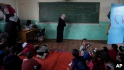 FILE - Manal Al Buhaisi works with children at a makeshift class in Deir al Balah, Gaza Strip, on April 21, 2024.