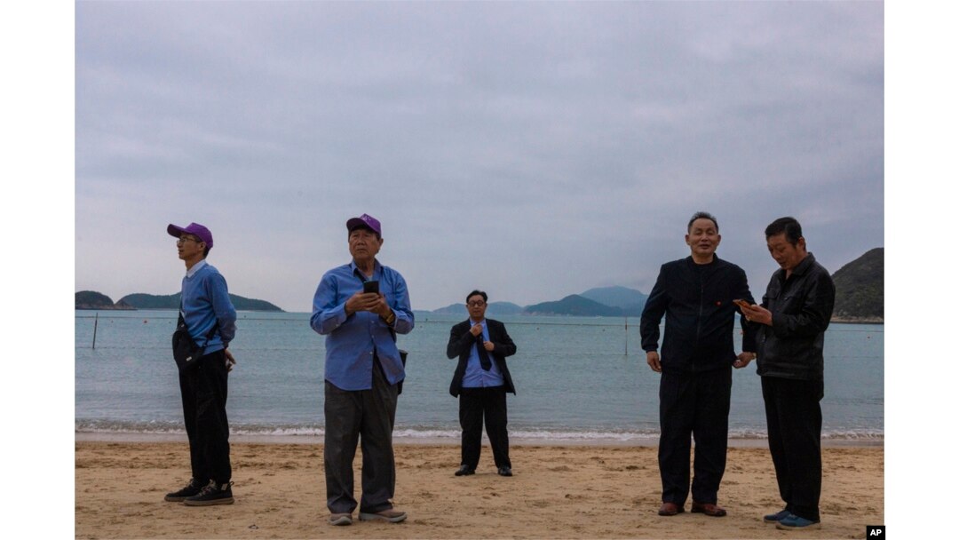FILE - Mainland Chinese tourists on a budget tour take photographs on a beach in Hong Kong, April 10, 2023.