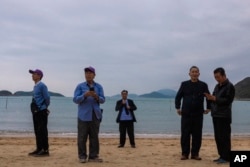 FILE - Mainland Chinese tourists on a budget tour take photographs on a beach in Hong Kong, April 10, 2023.