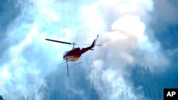 A helicopter heads toward a ridge to make a water drop on a wildland fire burning near the Ken Caryl Ranch development July 31, 2024, southwest of Littleton, Colo.