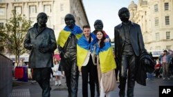 Aficionados colocan una bandera de Ucrania a una estatua en homenaje a los Beatles, antes de Eurovisión, en Liverpool, Inglaterra, el 12 de mayo de 2023. 