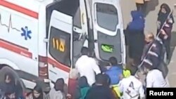 ১ মার্চ, ২০২৩ তারিখে প্রকাশিত এবং রয়টার্স দ্বারা প্রাপ্ত অপ্রকাশিত ভিডিও থেকে এই স্থির চিত্রটিতে ইরানের আরদাবিলে বিষক্রিয়ার রিপোর্টের পর একজনকে একটি মেয়েদের স্কুলের বাইরে একটি অ্যাম্বুলেন্সে তোলা হচ্ছে৷ (ফাইল ছবি) 