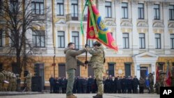 乌克兰总统泽连斯基（左）在纪念俄乌战争爆发一周年的纪念仪式上将一面新军旗授予乌克兰军队指挥官。（2023年2月24日）