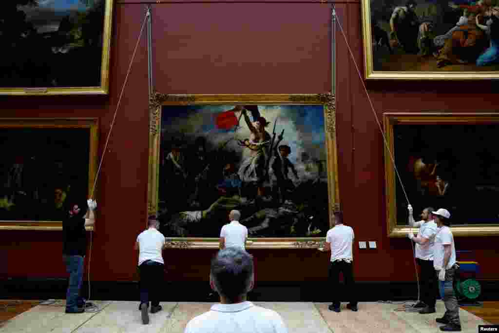 Employees install the painting &quot;La Liberte guidant le peuple, 1830&quot; (Liberty Leading the People) by Eugene Delacroix (1798-1863) after six months of restoration work, at the Louvre museum in Paris, France.