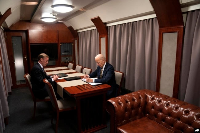 拜登总统在从乌克兰前往波兰的列车上与白宫国家安全顾问沙利文讨论纪念乌克兰战争爆发一周年的讲话稿。（2023年2月20日）