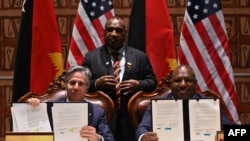 2023年5月22日，巴布亚新几内亚总理詹姆斯·马拉佩（中）在莫尔兹比港看着美国国务卿安东尼·布林肯（左）和巴布亚新几内亚国防部长温·巴克里·达基（右）在签署安全协议后展示文件。（法新社照片）