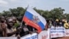Seorang demonstran memegang bendera Rusia dalam aksi menunjukkan dukungan terhadap keberadaan Rusia dan China di Republik Afrika Tengah, di ibu kota Bangui, pada 22 Maret 2023. (AFP/Barbara Debout)