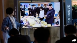 Lide Kore di No Kim Jong Un (a dwat) ak pitit fi li paret sou ekran televizyon an nan yon stasyon tren nan vil Seoul, kapital Kore di Sid, 19 Avril 2023. 