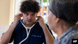 Dr. Pedro Juan Vázquez, better known by his stage name PJ Sin Suela, attends to a patient in Loiza, Puerto Rico, Saturday, May 25, 2024. (AP Photo/Alejandro Granadillo)