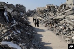 Palestinians walk past damage caused by an Israeli offensive in the Jabaliya refugee camp in the Gaza Strip on February 29, 2024.