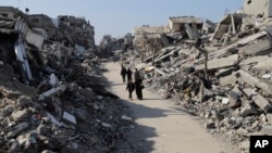 Palestinians walk through the destruction from the Israeli offensive in Jabaliya refugee camp in the Gaza Strip, Feb. 29, 2024.