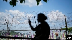 A visitor takes a photo near a wire fence decorated with ribbons with messages wishing for the reunification of the two Koreas at the Imjingak Pavilion in Paju, South Korea, June 26, 2024. 