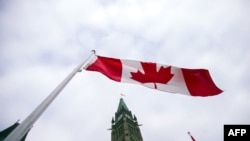 资料照片：2015年12月4日，加拿大渥太华国会山和平塔前飘扬着的加拿大国旗。（法新社照片）
