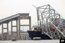 A cargo ship is stuck under the part of the structure of the Francis Scott Key Bridge after the ship hit the bridge, March 27, 2024, in Baltimore.