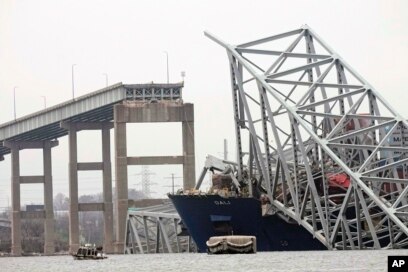A cargo ship is stuck under the part of the structure of the Francis Scott Key Bridge after the ship hit the bridge, March 27, 2024, in Baltimore.