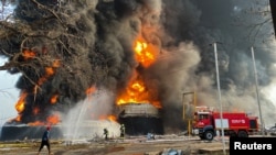 Firemen work to extinguish fire after a blast at an oil terminal in Conakry, Guinea, Dec. 18, 2023.