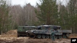 A Polish soldier helps navigate a Leopard 2 tank during training at a military base and test range in Swietoszow, Poland, Feb. 13, 2023.