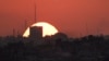 The sun sets behind the buildings in the Gaza Strip as seen from southern Israel, July 17, 2024.