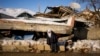 Zehra Kurukafa walks past a house in Polat, Turkey, destroyed during the recent 7.8 magnitude earthquake, Feb. 12, 2023. Some journalists covering the disaster have reported being harassed, detained or obstructed as they work to document the devastation.