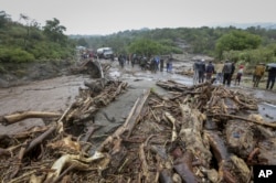 FILE — Passengers from stranded vehicles stand next to the debris from floodwaters, on the road from Kapenguria, in West Pokot county, in western Kenya, Nov. 23, 2019.