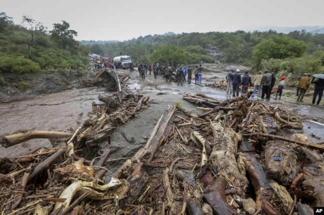 FILE — Passengers from stranded vehicles stand next to the debris from floodwaters, on the road from Kapenguria, in West Pokot county, in western Kenya, Nov. 23, 2019.