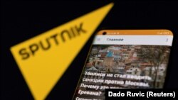 Aplikasi Sputnik terlihat di sebuah smartphone di depan logo Sputnik dalam ilustrasi yang diambil pada 28 Februari 2022. (Foto: REUTERS/Dado Ruvic)