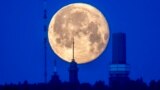 The moon sets behind buildings on top of the Feldberg mountain near Frankfurt, Germany, June 5, 2023.