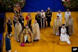 Raja Charles III mengenakan Mahkota St Edward dan Ratu Camilla mengenakan Mahkota Ratu Mary duduk saat upacara penobatan di Westminster Abbey, di London, Sabtu 6 Mei 2023. (Andrew Matthews via AP)