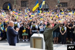Ukrainian President Volodymyr Zelenskyy, right, waves at the crowd as the public weaves Ukrainian and Danish flags in front of the Danish Parliament in Copenhagen, Denmark, in this handout photograph taken and released by the Ukrainian Presidential press service on Aug. 21, 2023.