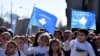 People wave Kosovar and Albanian flags as they watch a parade during celebrations of the 15th anniversary of Kosovo independence in Pristina, Kosovo, Feb. 17, 2023.