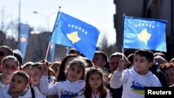 People wave Kosovar and Albanian flags as they watch a parade during celebrations of the 15th anniversary of Kosovo independence in Pristina, Kosovo, Feb. 17, 2023.