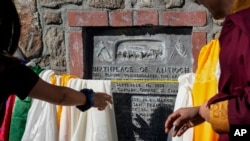 Buddhist faith leaders and community members drape Tibetan prayer scarves on the Birthplace of Antioch marker during the "May We Gather" pilgrimage in Antioch, California, March 16, 2024.