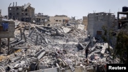 Palestinians search for belongings through the rubble in the aftermath of an Israeli strike near a U.N.-run school sheltering displaced people, in Khan Younis, in the southern Gaza Strip, July 4, 2024.