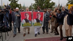 Newly-elected lawmakers display posters of their leader, imprisoned former Prime Minister Imran Khan, as they arrive for the opening session of parliament, in Islamabad, Pakistan, Feb. 29, 2024.