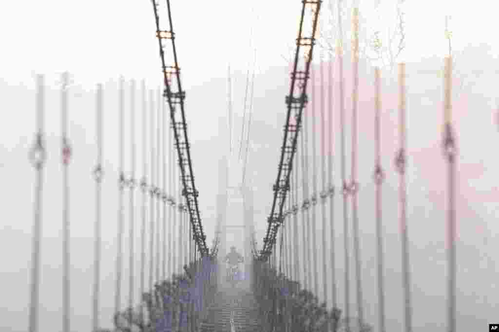 A man on a motorcycle crosses a suspension bridge over the Bagmati river in Lalitpur, Nepal.
