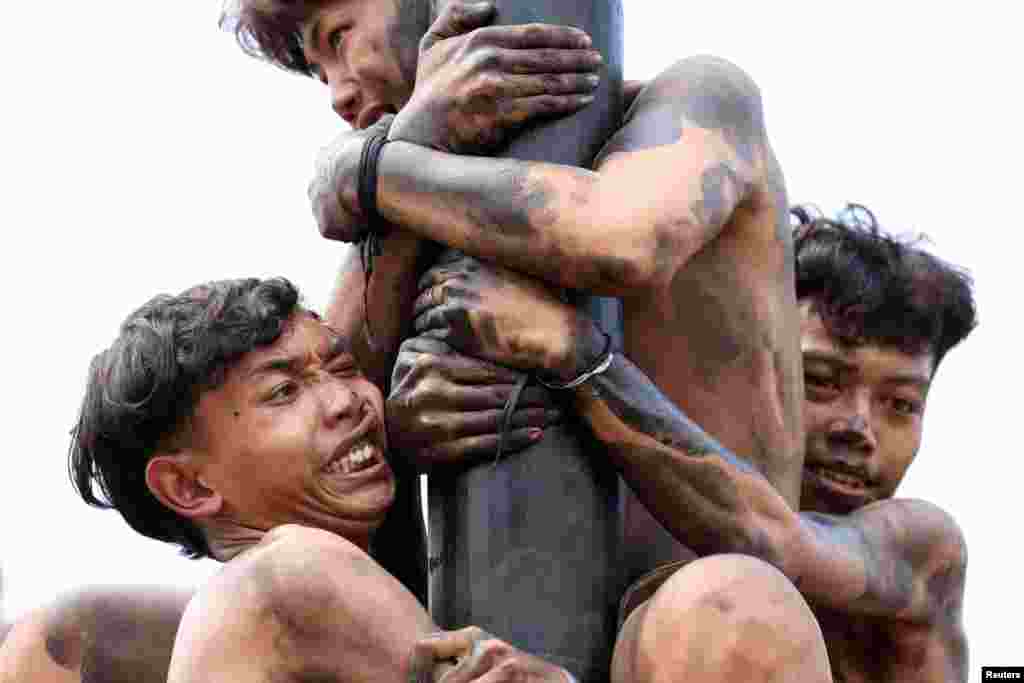 Participants try to reach the top of a greased pole to collect the prizes, during a &quot;Panjat Pinang&quot; competition, that is held to celebrate Indonesia&#39;s 79th Independence Day at Ancol in Jakarta, Aug. 17, 2024.